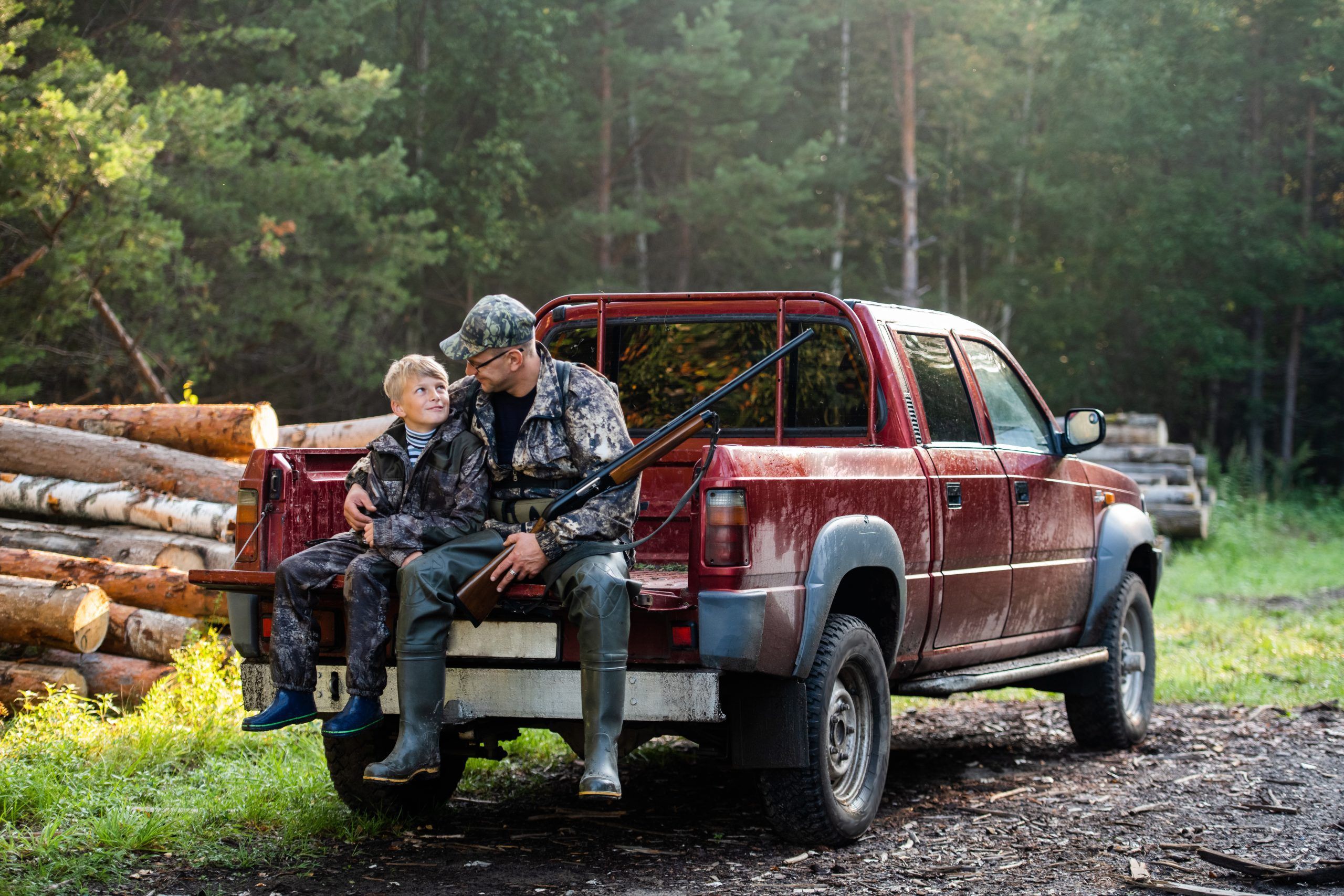 Father and son sitting together in truck outdoors with shotgun hunting gear. Father and son sitting together in truck outdoors with shotgun hunting gear.